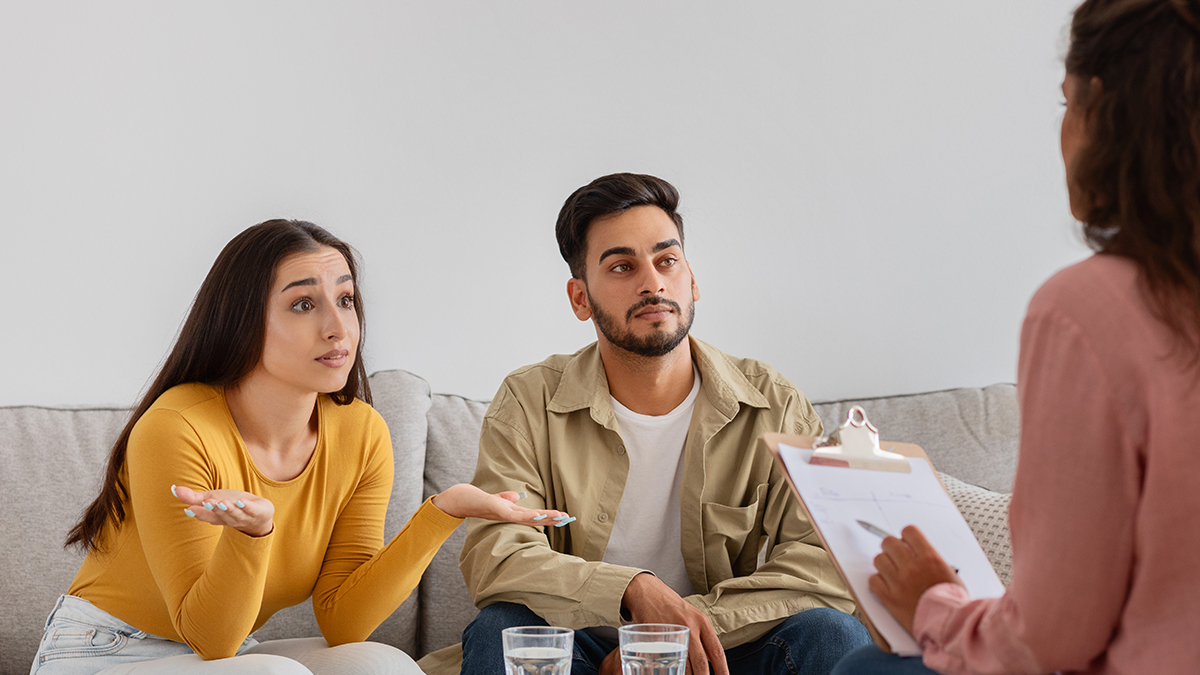 Two people in conversation with a counsellor during a relationship counselling session