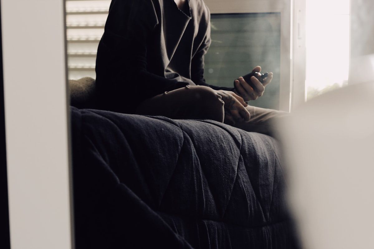 A young adult sitting on a sofa looking at a phone